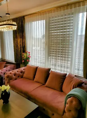 a living room with a brown couch in front of windows at HELGA apartmani BOSS i PRESIDENT in Kraljevo