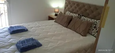 a white bed with two blue pillows on it at Apartman '' PETICA'' in Vrnjačka Banja