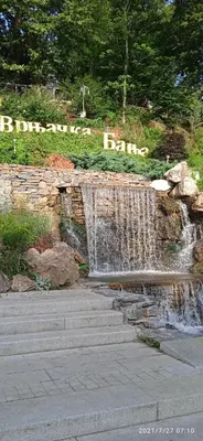 a waterfall in a park next to a stone wall at Apartman '' PETICA'' in Vrnjačka Banja