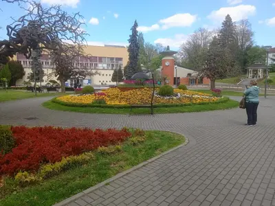 a man standing in front of a park with flowers at Apartman '' PETICA'' in Vrnjačka Banja