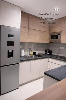 a kitchen with white cabinets and a stainless steel refrigerator at Leo Lux 2 in Niš