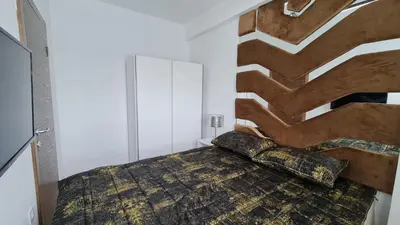 a bedroom with a bed with a wooden headboard at RELAX LUX AKVA PARK(K-KOMPLEX) in Jagodina
