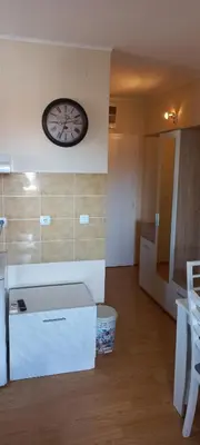 a room with a clock on the wall and a kitchen at Studio Isidora in Vrnjačka Banja