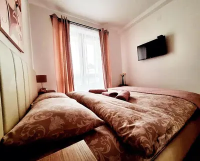a bedroom with two beds and a large window at Iskra Sparkle apartman in Soko Banja