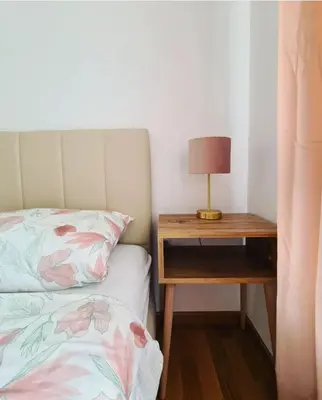 a bed and a nightstand with a lamp on a table at Iskra Sparkle apartman in Soko Banja