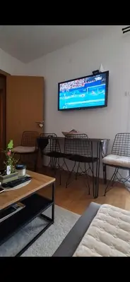 a living room with a table and a tv on the wall at Iskra Sparkle apartman in Soko Banja