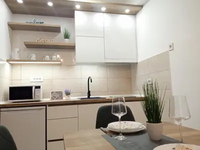 a kitchen with white cabinets and a table with chairs at Apartman Zara - free private parking - in Jagodina