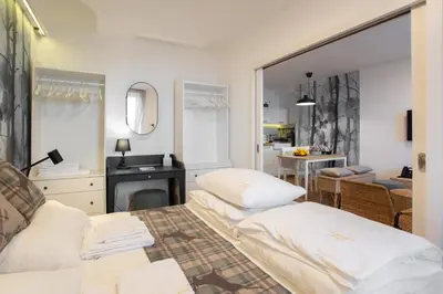 a bedroom with two beds and a desk and a kitchen at Cardak u Sumi (Forest house) in Kopaonik