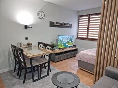 a living room with a dining room table and a bedroom at Apartman 