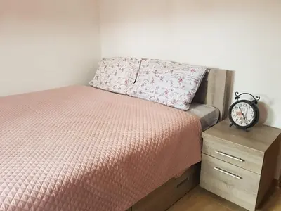 a bed with a pillow and a clock on a nightstand at TRG In in Vrnjačka Banja