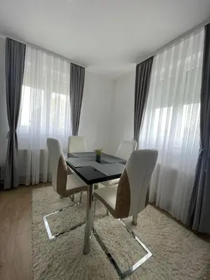 a dining table and chairs in a room with windows at TRG In in Vrnjačka Banja