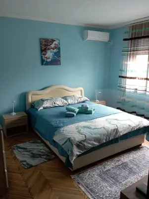a bedroom with a bed with a blue wall at Apartman Miki Jovanović in Pirot