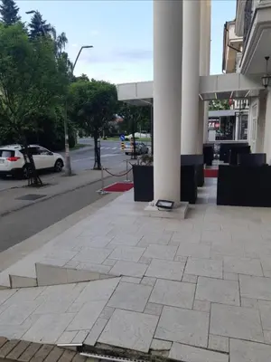 a building with columns on a sidewalk with a street at Apartman STEVAN Vrnjačka Banja in Vrnjačka Banja