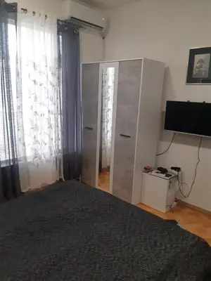 a bedroom with a bed and a television and curtains at Apartman STEVAN Vrnjačka Banja in Vrnjačka Banja