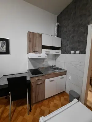 a kitchen with white cabinets and a sink and a table at Apartman STEVAN Vrnjačka Banja in Vrnjačka Banja