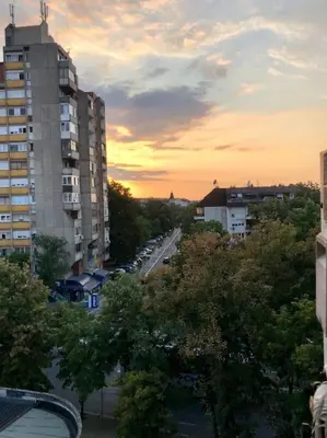 a city street at sunset with buildings and trees at Lovely 1-bedroom condo with available parking in Kraljevo
