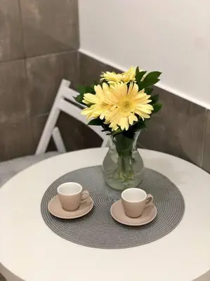 a table with two cups and a vase of flowers at Lovely 1-bedroom condo with available parking in Kraljevo