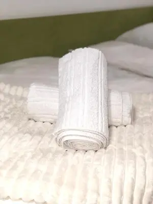 a stack of white towels on a bed at Apartman TADIJA Niš in Donja Vrežina