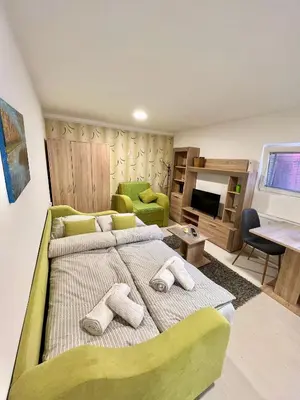 a bedroom with a large bed and a living room at Apartman TADIJA Niš in Donja Vrežina