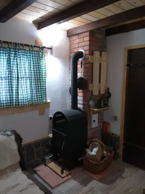 a room with a brick fireplace and a stove at Vila Golija in Raška