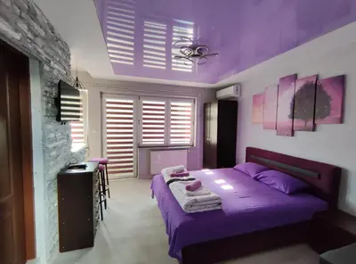 a purple bedroom with a bed and a table at Centrum Lux Apartment in Niš