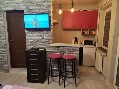 a kitchen with two stools and a tv on a stone wall at Centrum Lux Apartment in Niš
