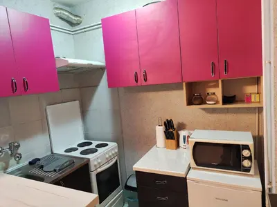 a small kitchen with pink cabinets and a microwave at Centrum Lux Apartment in Niš