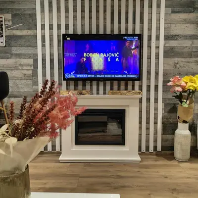 a living room with a fireplace with a flat screen tv at Apartman OGLEDALO in Zaječar
