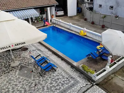 a swimming pool with two chairs and an umbrella at Vila Jovana A in Rogljevo