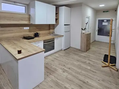 a kitchen with white cabinets and a wooden floor at Apartman LENI2 u centru Zajecara in Zaječar