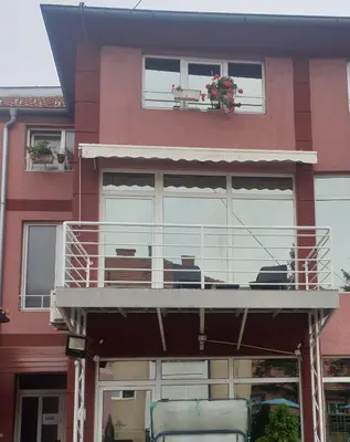 a building with a balcony with chairs on it at Apartman LENI2 u centru Zajecara in Zaječar