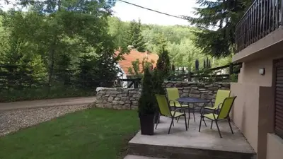 a patio with a table and chairs and a stone wall at Apartmani Damjan Vlasinsko jezero in Surdulica