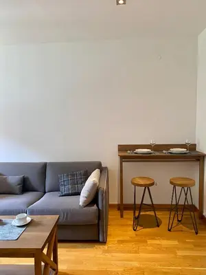 a living room with a couch and a table with two stools at Apartman 20, Brzeće Centar in Brzeće