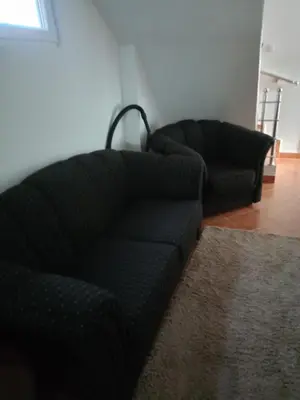 a living room with two black couches and a rug at Gostinska kuća in Leskovac