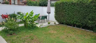 a garden with a table and an umbrella and a hedge at Gostinska kuća in Leskovac