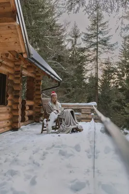 a woman sitting on a bench in the snow at Casa Montana in Kopaonik