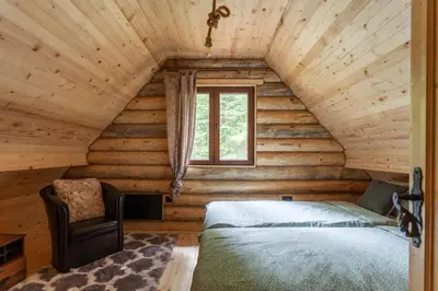 a bedroom in a log cabin with a bed and a window at Casa Montana in Kopaonik