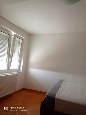 a white room with a bed and two windows at Apartman Simović, Vrnjačka Banja in Vrnjačka Banja