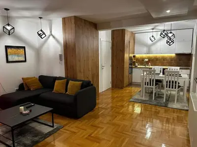 a living room with a couch and a table and a kitchen at Riverside apartment with private parking in Niš