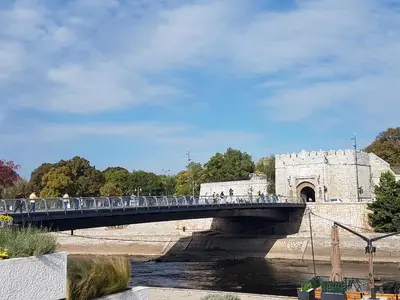a bridge over a river with people walking on it at Riverside apartment with private parking in Niš