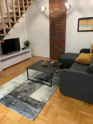 a living room with a couch and a table at Riverside apartment with private parking in Niš