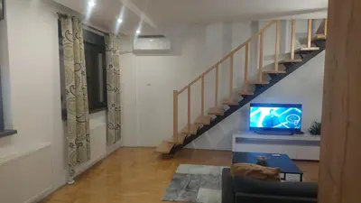 a living room with a staircase and a tv at Riverside apartment with private parking in Niš