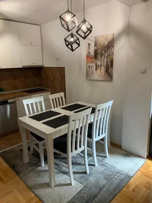 a dining room with a white table and chairs at Riverside apartment with private parking in Niš