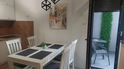 a white table and chairs in a kitchen with a plant at Riverside apartment with private parking in Niš