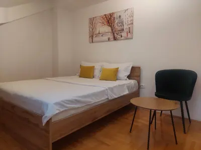 a small bedroom with a bed and a chair at Riverside apartment with private parking in Niš