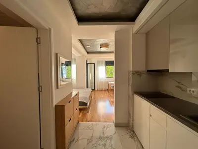 a kitchen with white cabinets and a living room at Centar Crnjanski 1 in Jagodina
