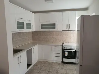 a white kitchen with white cabinets and a refrigerator at Big apartman - Free parking in Vranje