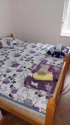 a bed with a floral comforter and towels on it at Big apartman - Free parking in Vranje
