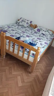 a wooden bed in a room with a wooden floor at Big apartman - Free parking in Vranje