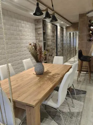 a dining room with a wooden table and white chairs at Premium Urban Life in Zaječar
